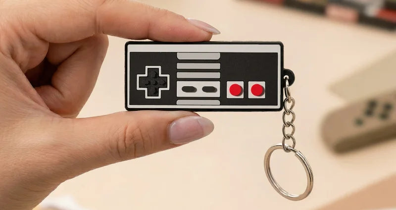 Hand holding a keychain shaped like a classic video game controller