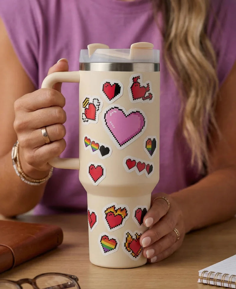 Person holding a mug with heart designs on a wooden table