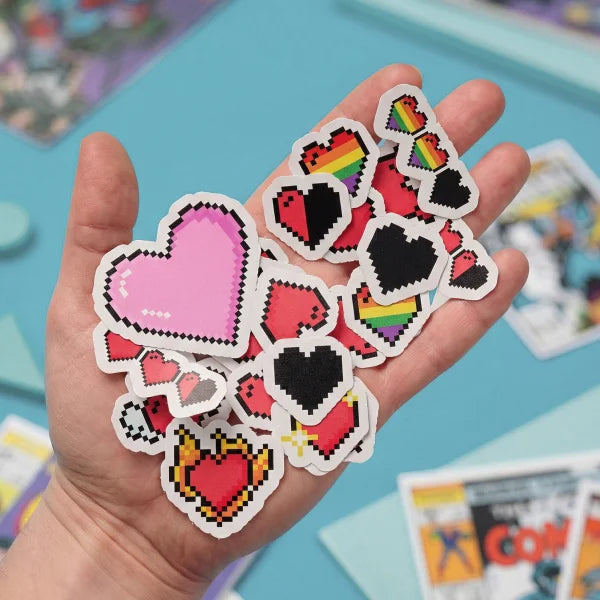 Hand holding pixelated heart-shaped stickers with a colorful background