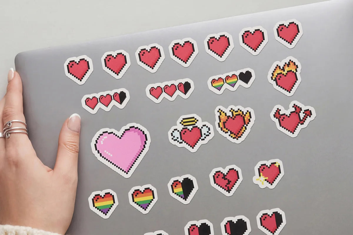 Laptop with various heart-shaped stickers on a light gray background